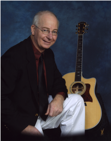 Larry Miller, sitting in front of a guitar with a blue background